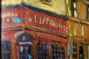 Close-up view of the shop sign in Robert Antoine Pinchon’s street scene painting.